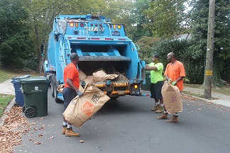Public Works workers collecting yard debris bags in a neighborhood. 